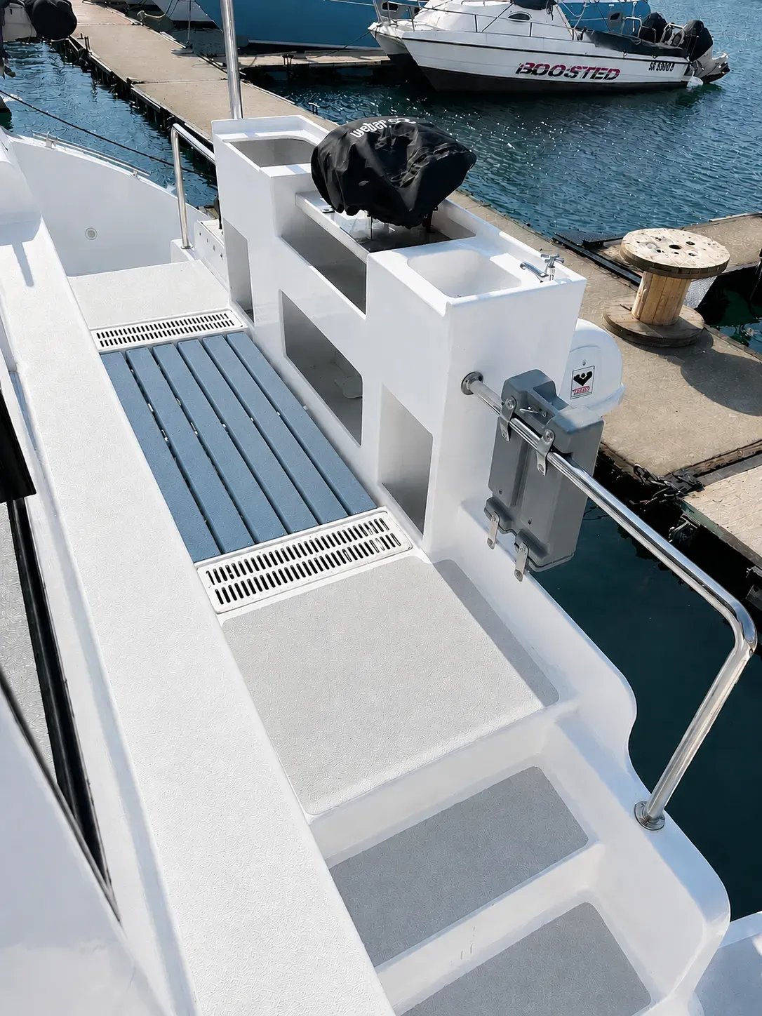 Vaquita's aft deck with a covered gas braai, freshwater sink, and a stepped sugar scoop leading down to the water.