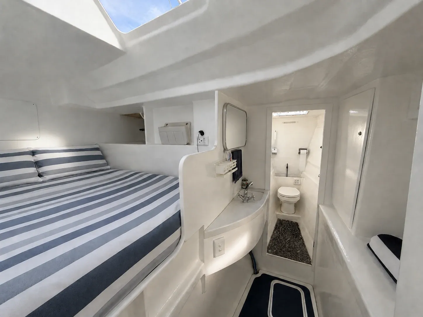 Forward double cabin aboard Vaquita: a striped berth beside a private ensuite with hand basin and electric toilet.