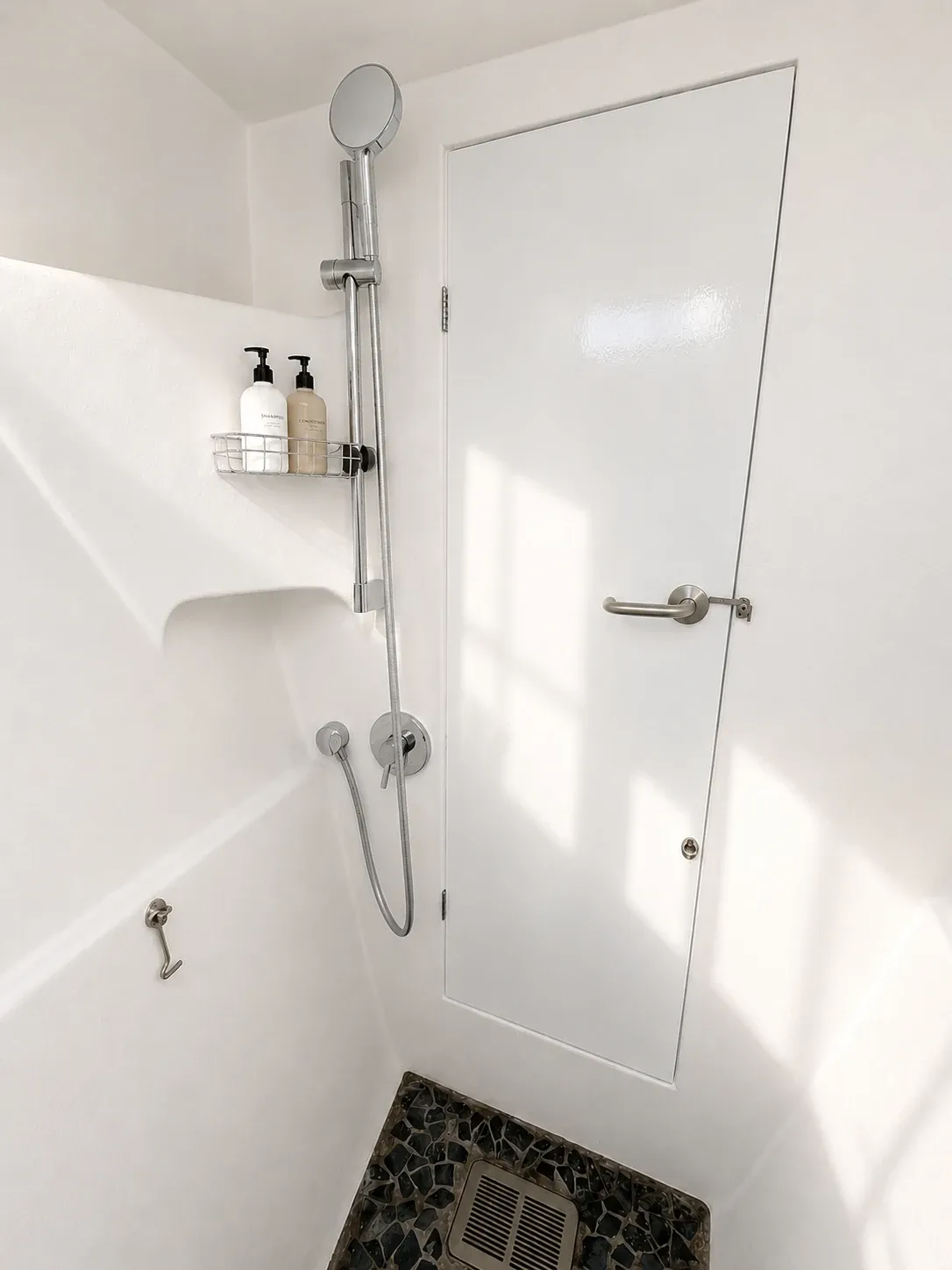 Ensuite shower compartment with a handheld shower, mixer tap, and toiletry shelf.