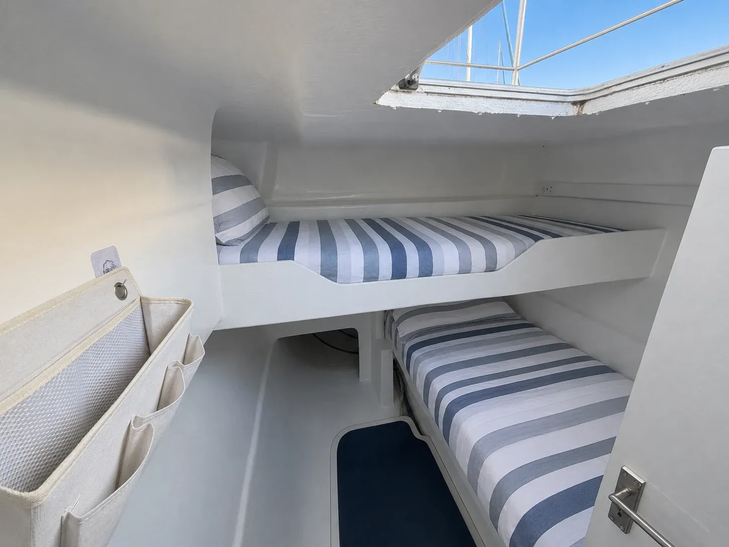 Aft twin-berth cabin aboard Vaquita with two single bunks lit by an overhead hatch.