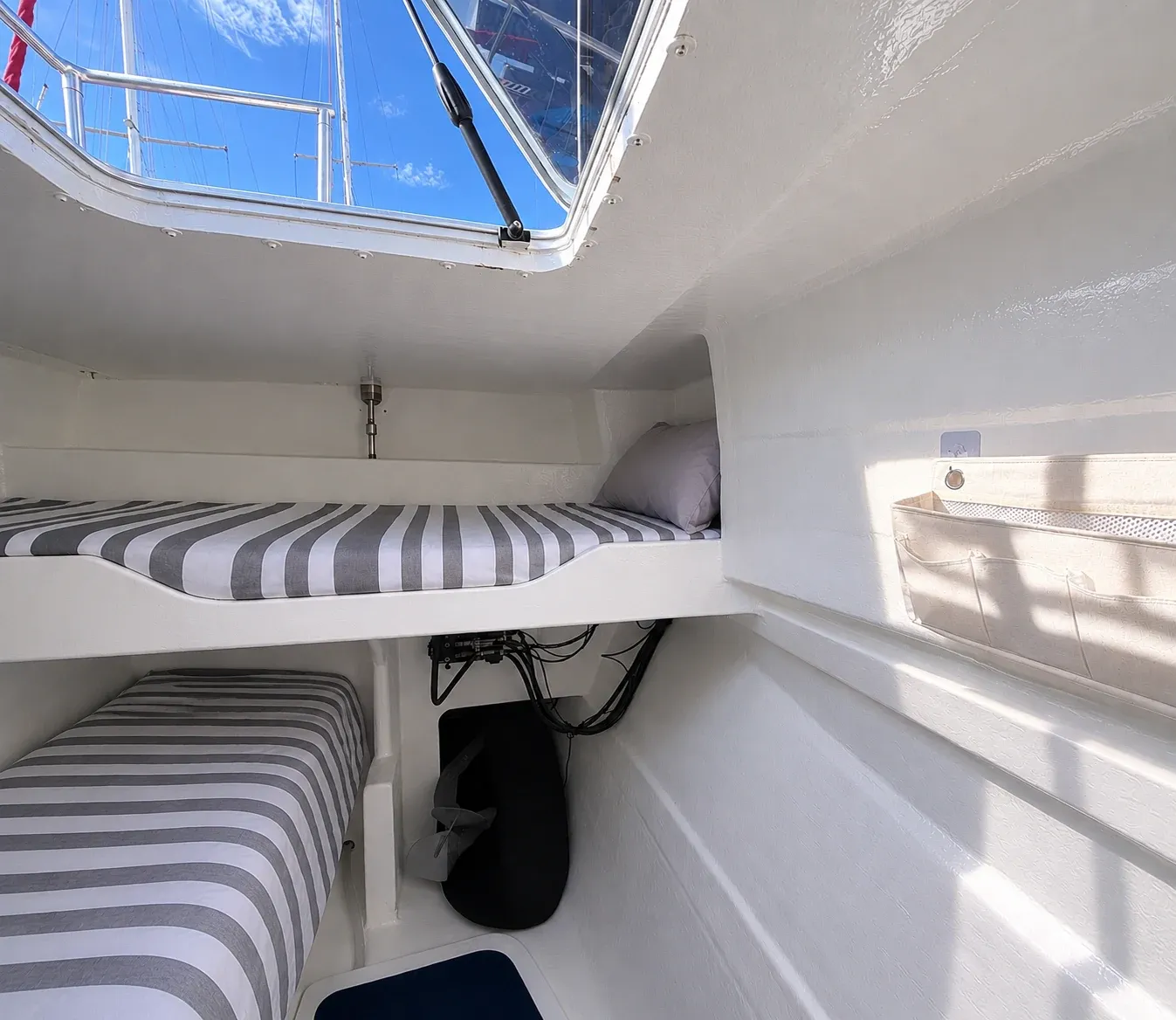 Aft twin-berth cabin with stacked single bunks and natural light from an overhead hatch.