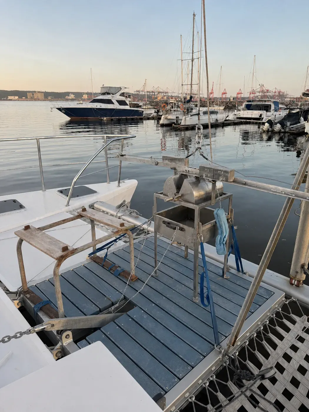 Stainless grab sampler resting in its deck cradle aboard Vaquita, rigged to the foredeck hoist with lifting straps.
