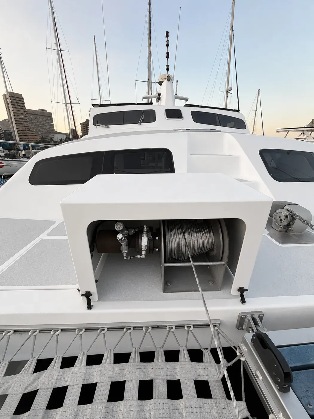 Foredeck hydraulic winch aboard Vaquita: a steel cable drum and hydraulic motor housed beneath a white deck cowling.