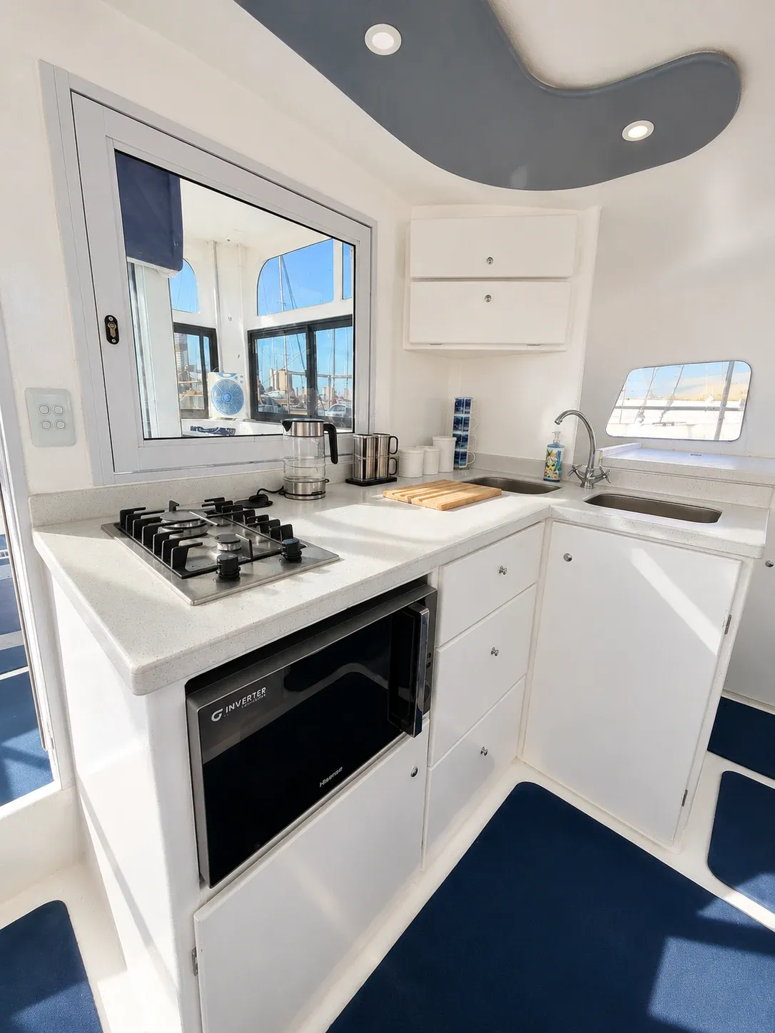 Vaquita's galley with a gas stove, microwave oven, double stainless sink, and a window over the counter.