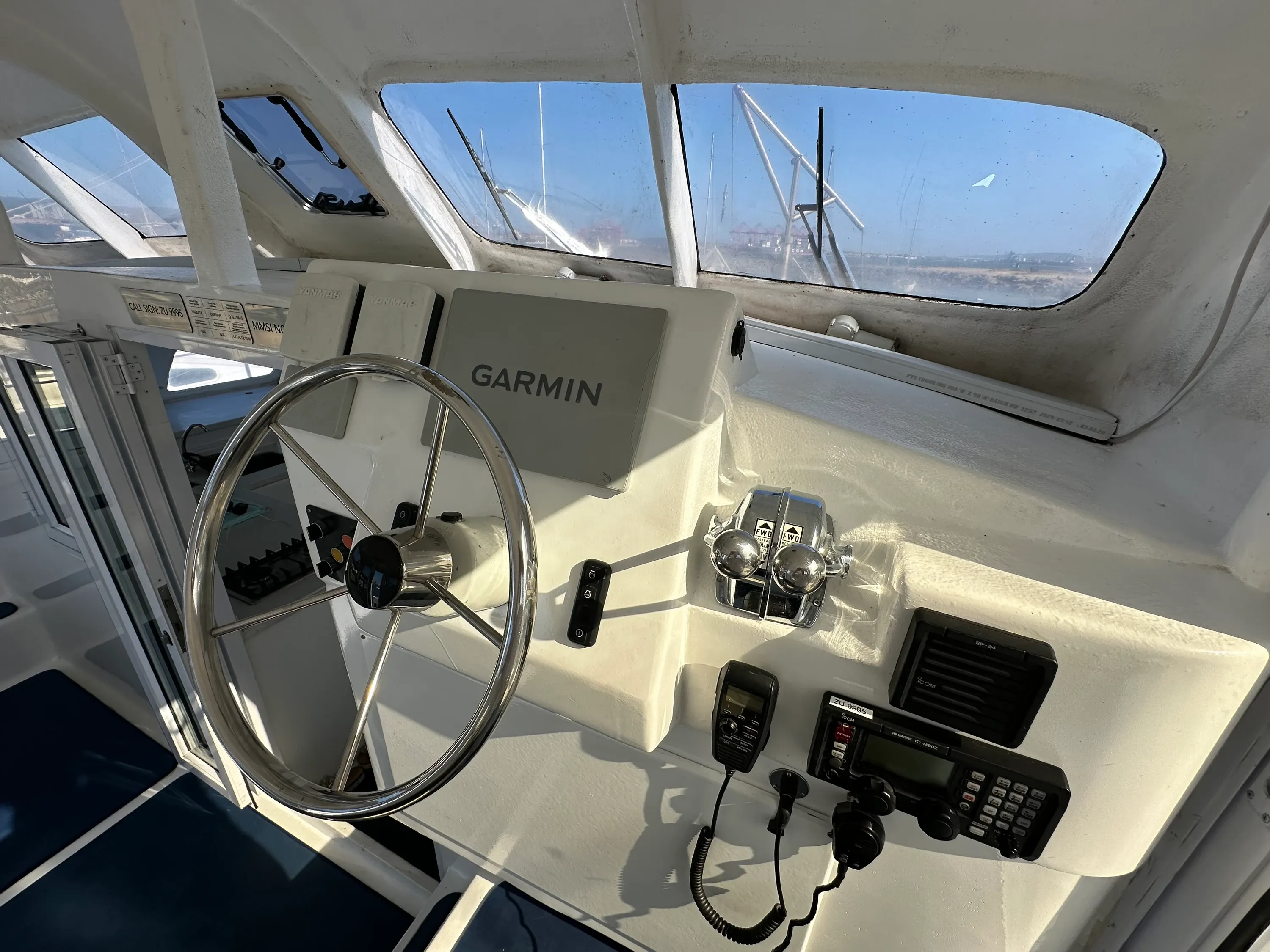 Vaquita's helm station: stainless wheel, Garmin chart plotter, single-lever throttle, and VHF and AIS radios mounted to the console.